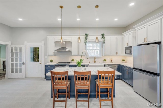 100 Lewis St, Troy, MO 63379 - kitchen with appliances with stainless steel finishes, wall chimney exhaust hood, a sink, a breakfast bar area, and a center island