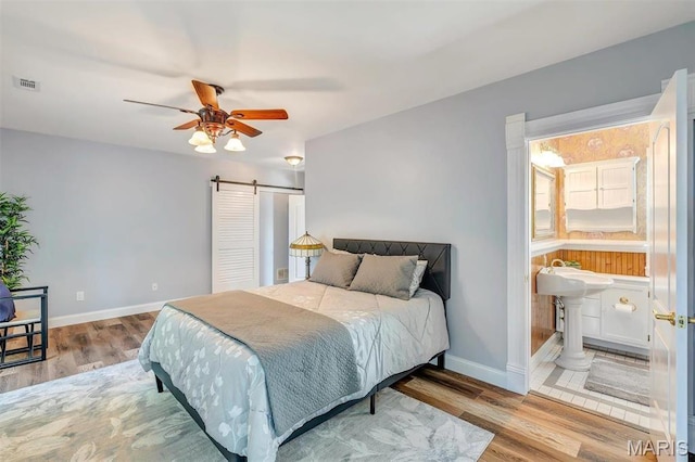 100 Lewis St, Troy, MO 63379 - bedroom featuring a barn door, wood finished floors, baseboards, and connected bathroom