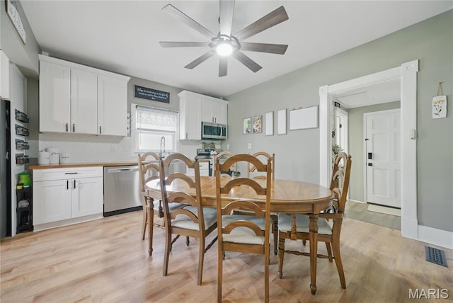 dining area with light wood finished floors and a ceiling fan