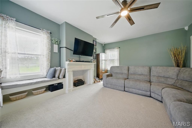 living area featuring carpet floors, a ceiling fan, and a fireplace with flush hearth