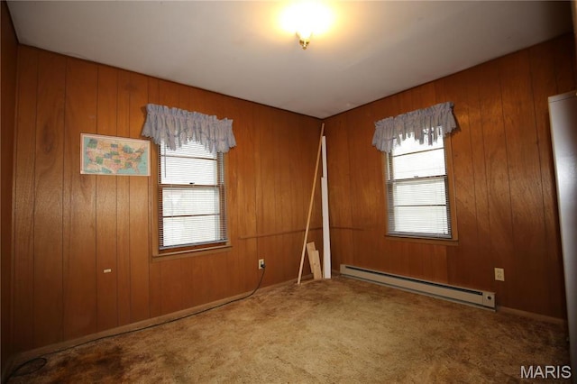 carpeted spare room with baseboard heating, healthy amount of natural light, and wood walls