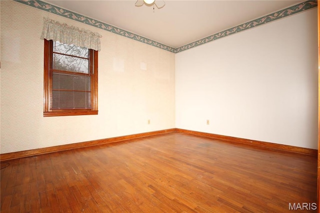 unfurnished room with baseboards and wood-type flooring