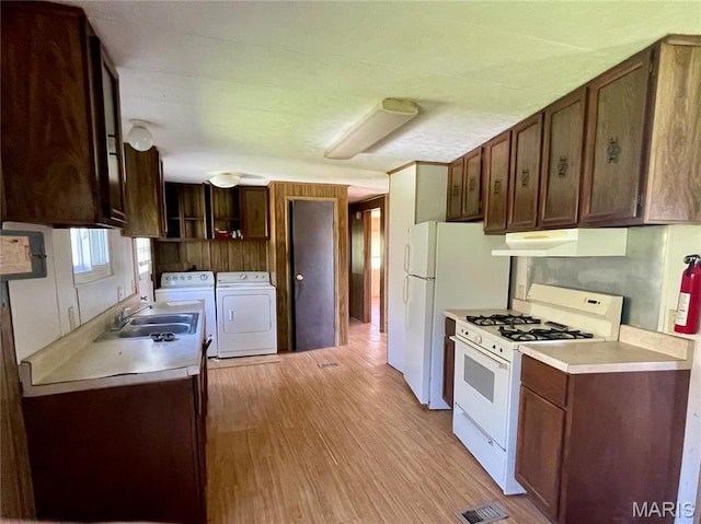 12678 Hyfield Rd, De Soto, MO 63020 - kitchen featuring white appliances, washing machine and dryer, under cabinet range hood, a sink, and light wood-style flooring