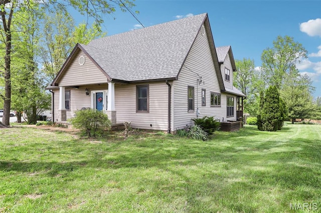 view of front of home with a front yard and a shingled roof