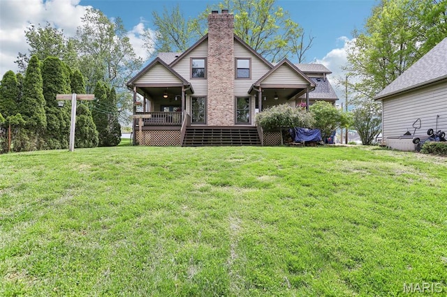 back of house featuring a chimney, a lawn, and a deck