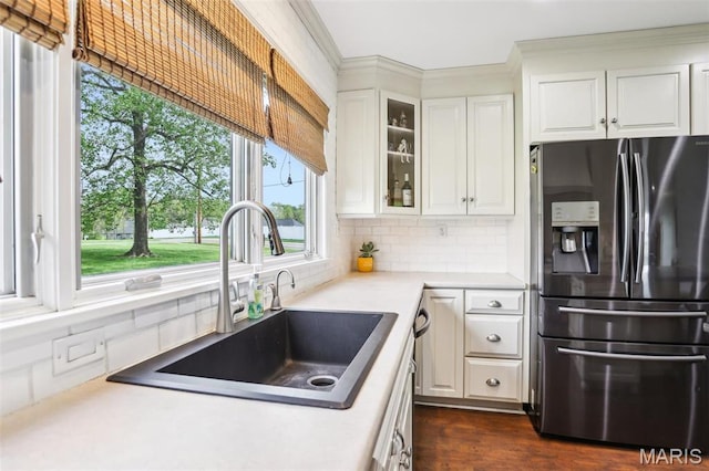 kitchen featuring stainless steel fridge with ice dispenser, a sink, plenty of natural light, backsplash, and crown molding