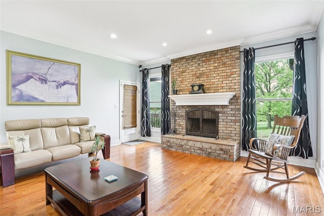 living room with crown molding, hardwood / wood-style floors, a brick fireplace, baseboards, and recessed lighting