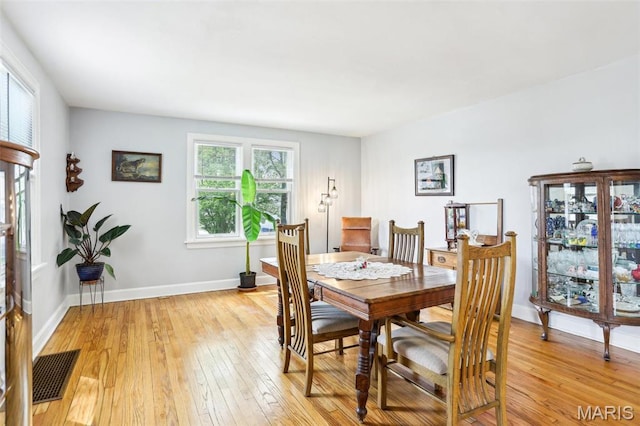 dining space featuring light wood-type flooring and baseboards