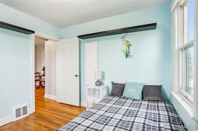 bedroom with wood finished floors, multiple windows, and baseboards