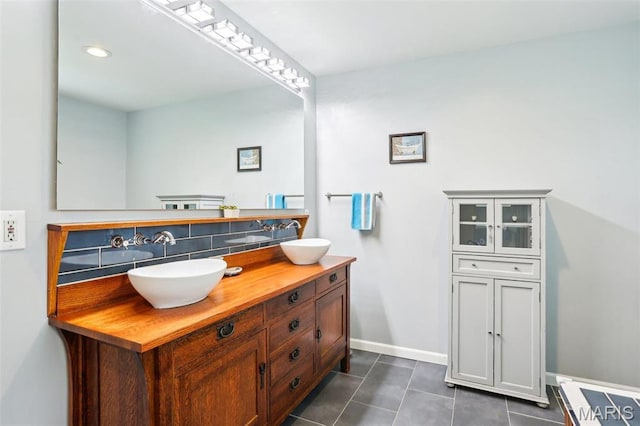 bathroom with tile patterned flooring, baseboards, double vanity, and decorative backsplash