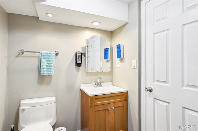 half bathroom featuring vanity, toilet, and recessed lighting