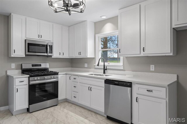 1399 Valli Ln, Saint Charles, MO 63304 - kitchen featuring appliances with stainless steel finishes, a sink, a chandelier, light marble finish flooring, and light countertops
