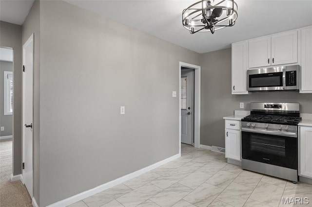1399 Valli Ln, Saint Charles, MO 63304 - kitchen featuring stainless steel appliances, a chandelier, light marble finish floors, light countertops, and baseboards