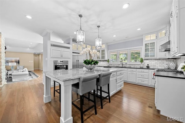 27 Lake Forest Cir, Lake St Louis, MO 63367 - kitchen featuring stainless steel appliances, crown molding, tasteful backsplash, a breakfast bar area, and a center island