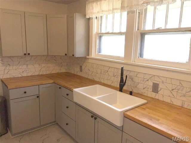 2538 Jerden Ave, Granite City, IL 62040 - kitchen with a sink, decorative backsplash, butcher block countertops, light marble finish floors, and white cabinets