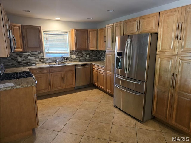 kitchen with stainless steel appliances, a sink, backsplash, light tile patterned floors, and stone counters