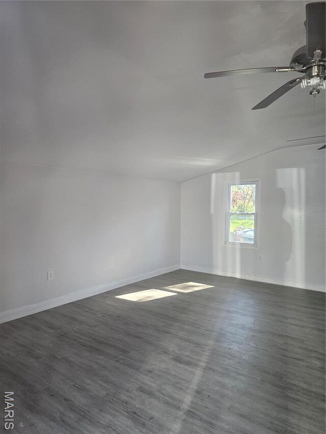spare room featuring a ceiling fan, baseboards, wood finished floors, and vaulted ceiling