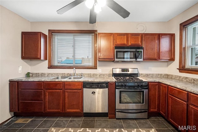 kitchen featuring stainless steel appliances, a sink, light countertops, a ceiling fan, and dark tile patterned flooring