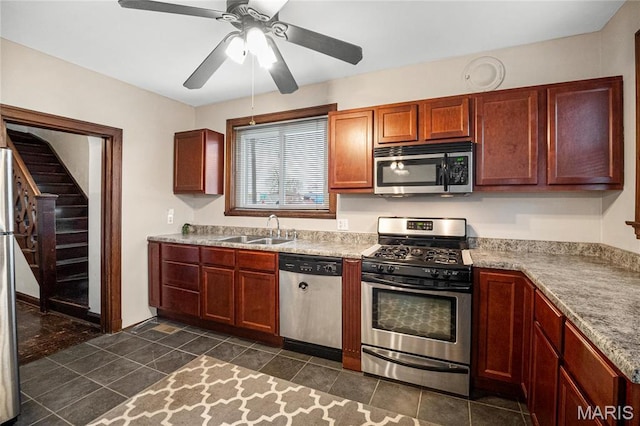 kitchen featuring appliances with stainless steel finishes, a sink, ceiling fan, dark tile patterned flooring, and light countertops