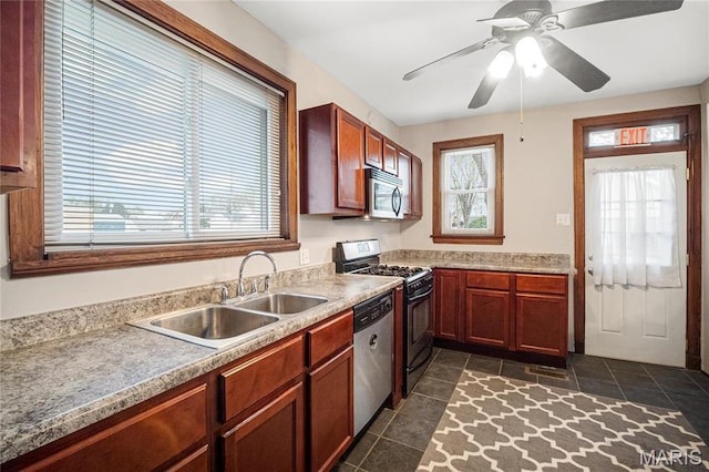 kitchen featuring stainless steel appliances, a sink, dark tile patterned flooring, and a ceiling fan
