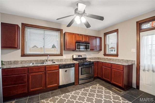 kitchen featuring stainless steel appliances, a sink, light countertops, dark tile patterned flooring, and ceiling fan