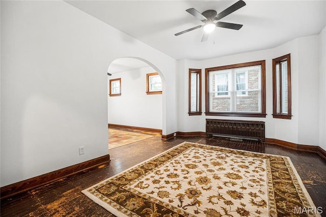 foyer featuring radiator heating unit, arched walkways, ceiling fan, and healthy amount of natural light
