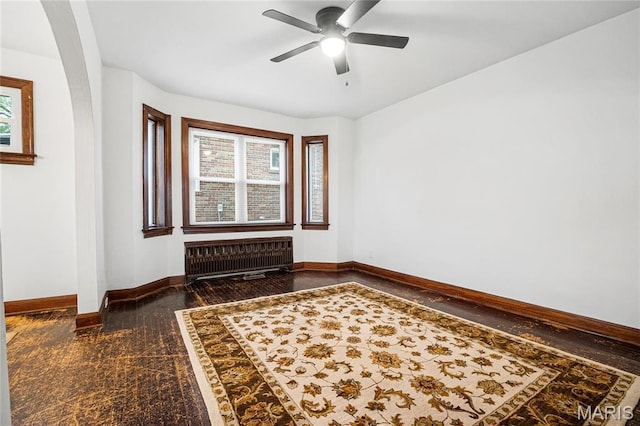unfurnished room featuring radiator heating unit, baseboards, and a ceiling fan