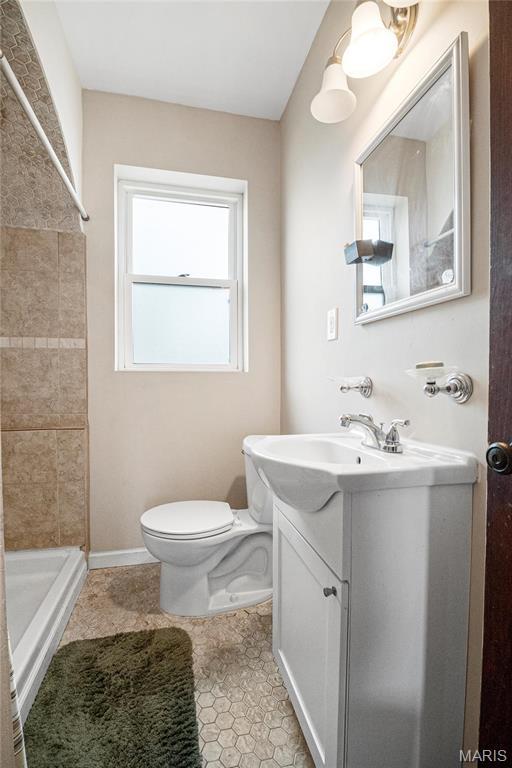full bath with a stall shower, toilet, vanity, and tile patterned floors
