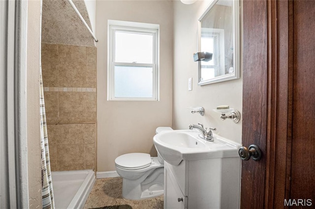 bathroom with a shower stall, toilet, vanity, and baseboards