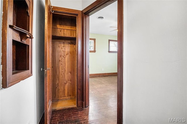 corridor featuring dark wood-style flooring and baseboards