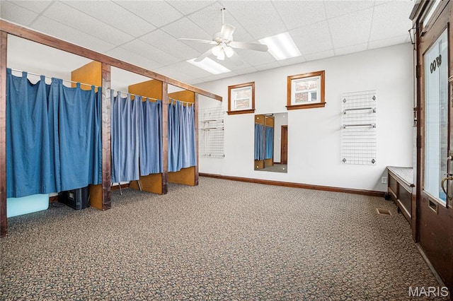 carpeted spare room with a ceiling fan, a drop ceiling, and baseboards