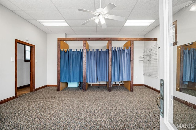 carpeted empty room featuring a paneled ceiling, baseboards, and a ceiling fan
