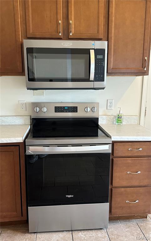 698 Carriage Ln, Hazelwood, MO 63042 - kitchen with stainless steel appliances, light countertops, and brown cabinets