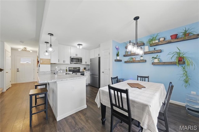 kitchen with stainless steel appliances, a sink, a peninsula, and dark wood-type flooring