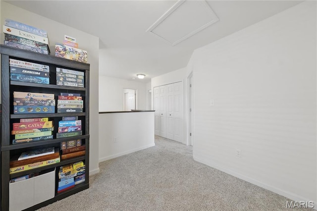 carpeted spare room featuring attic access and baseboards