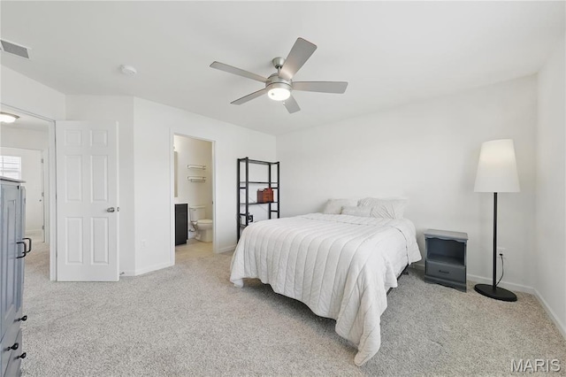 bedroom with light colored carpet, baseboards, a ceiling fan, and ensuite bath
