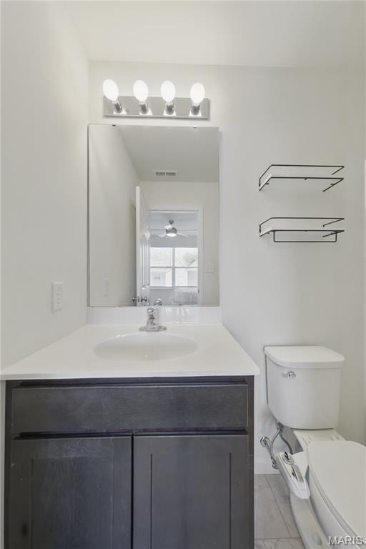 bathroom with vanity, toilet, and marble look tile flooring