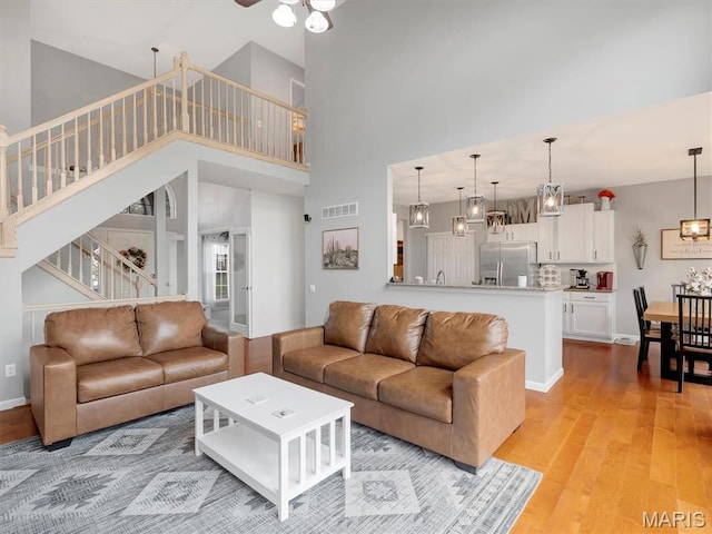 535 Vista Hills Ct, Eureka, MO 63025 - living area with a towering ceiling, stairway, light wood-style floors, ceiling fan, and baseboards