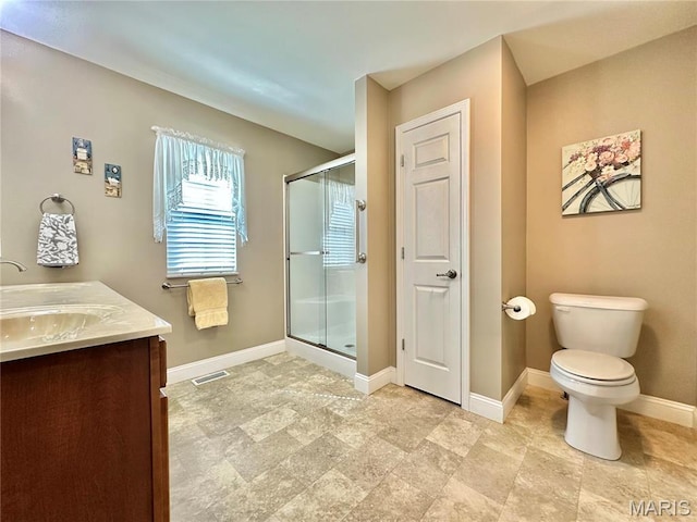 bathroom featuring a stall shower, toilet, baseboards, and vanity