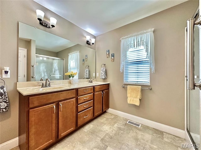 bathroom featuring a stall shower, baseboards, and double vanity