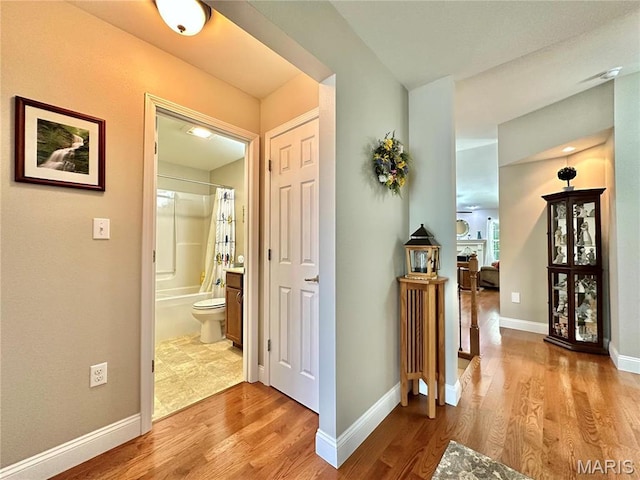 hall featuring light wood finished floors and baseboards