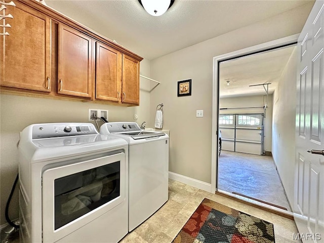 laundry area with washing machine and dryer, cabinet space, and baseboards