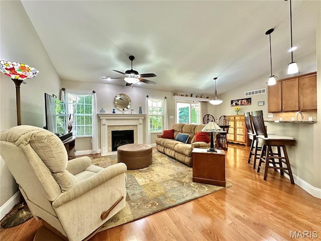 living room featuring lofted ceiling, ceiling fan, plenty of natural light, and light wood-style floors