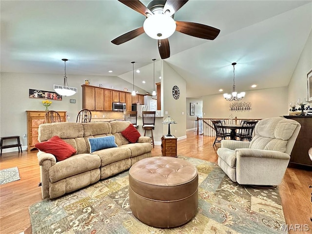living room featuring lofted ceiling, a chandelier, light wood-style flooring, a ceiling fan, and recessed lighting