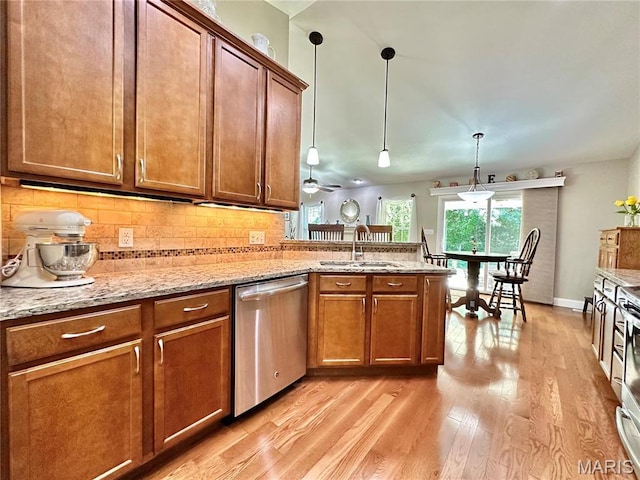 kitchen featuring stainless steel dishwasher, a sink, light wood-type flooring, a peninsula, and brown cabinets