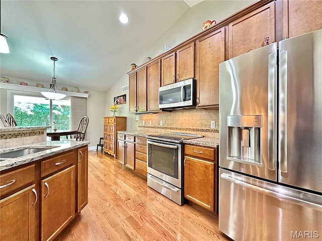 kitchen with stainless steel appliances, lofted ceiling, brown cabinetry, decorative backsplash, and a sink