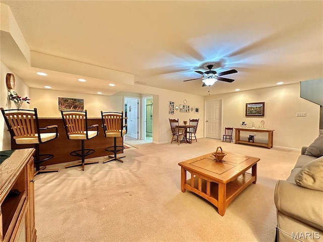 living area featuring light carpet, recessed lighting, ceiling fan, baseboards, and a dry bar