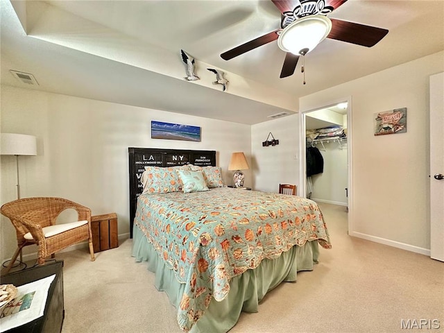 bedroom featuring light colored carpet, baseboards, a walk in closet, and a ceiling fan