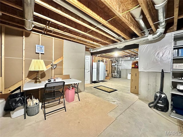 unfinished basement with freestanding refrigerator