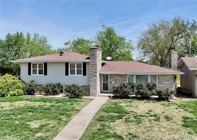 split level home featuring a chimney, stone siding, a front yard, and a shingled roof